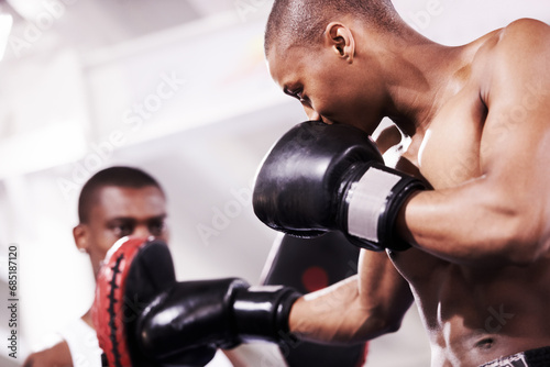 Black man, boxing and personal trainer in self defense or ring fight at gym workout, exercise or indoor training together. African male person, boxer or sparing partner preparing sports competition © Marine Gastineau/peopleimages.com