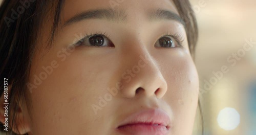 An Asian female student in a white school uniform is looking blankly upwards. photo