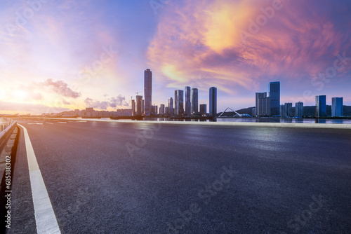 Asphalt highway road and city skyline with modern buildings at sunset