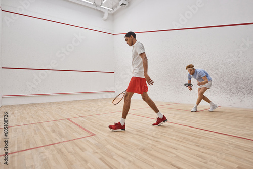 active and diverse men in sportswear playing squash inside of court, challenge and motivation