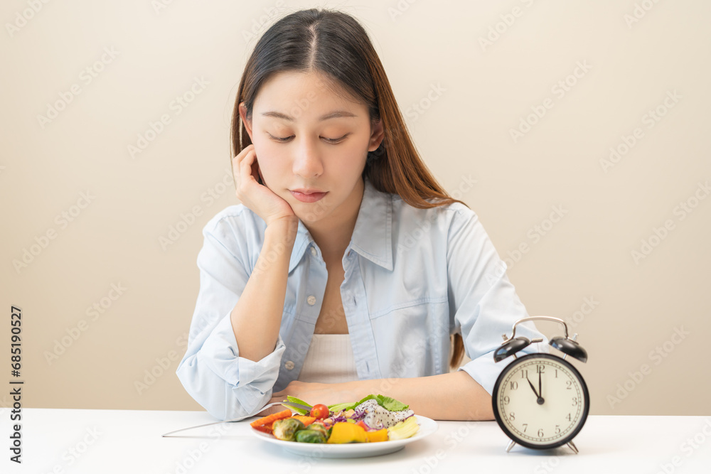 Intermittent fasting with clock, close up young woman, girl diet, waiting time to eat ketogenic low carb, green vegetable salad on plate. Eat food healthy first meal on brunch, lunch on table at home. Intermittent fasting with clock, close up young woman, girl diet, waiting time to eat ketogenic low carb, green vegetable salad on plate. Eat food healthy first meal on brunch, lunch on table at home.