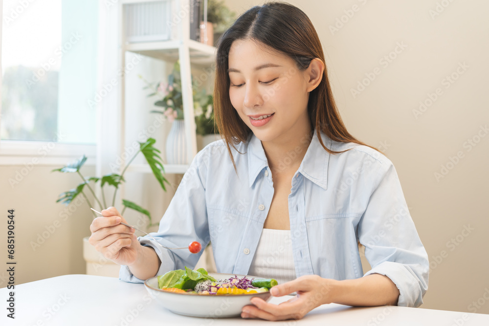 Diet concept, happy asian young woman hand use a fork to prick tomato, fresh vegetable or green salad, eat nutrition food on table at home, low fat to good body. Girl getting weight loss for healthy. Diet concept, happy asian young woman hand use a fork to prick tomato, fresh vegetable or green salad, eat nutrition food on table at home, low fat to good body. Girl getting weight loss for healthy.