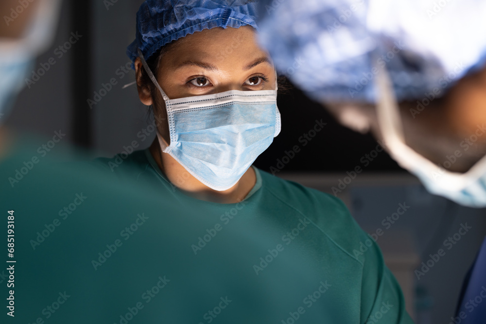 Diverse male and female surgeons with face masks doing surgery in hospital operating room Diverse male and female surgeons with face masks doing surgery in hospital operating room