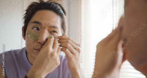 Gay queer man non-binary beauty blogger makeup artist at home cross dressing up apply face skin care eye make up brush. Real asia LGBT young guy adult people happy relax smile looking at mirror pride. photo