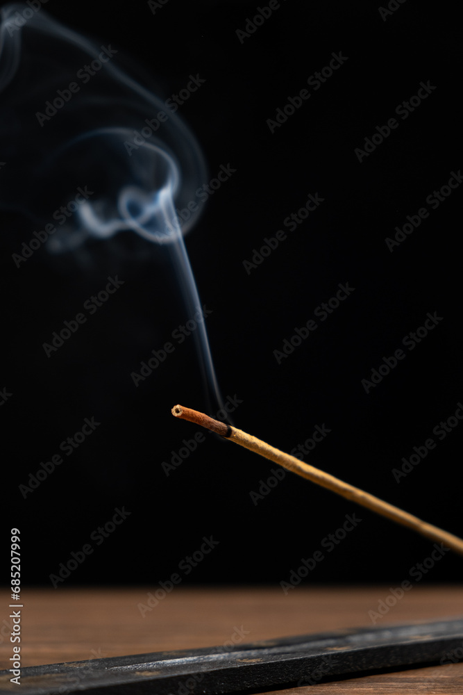 Smoke from a burning aroma stick on a black background. Incense sticks, aromatherapy and meditation. Smoke from a burning aroma stick on a black background. Incense sticks, aromatherapy and meditation.
