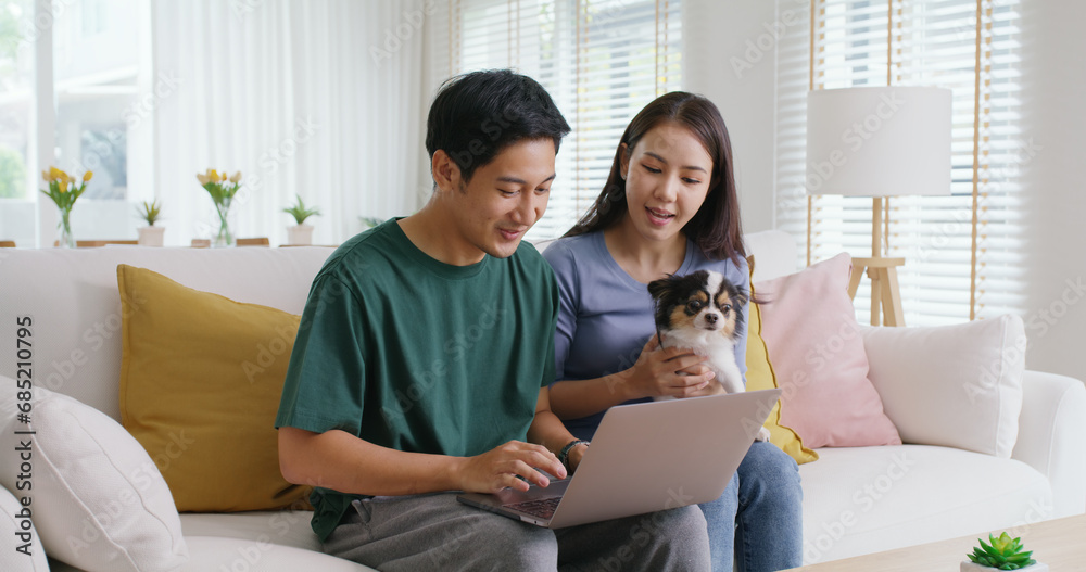 Asia people young family man woman smile happy sit at home sofa couch pay for hotel booking, search choose, buy ticket on laptop social media app travel trip getaway plan tour with cute small pet dog. Asia people young family man woman smile happy sit at home sofa couch pay for hotel booking, search choose, buy ticket on laptop social media app travel trip getaway plan tour with cute small pet dog.