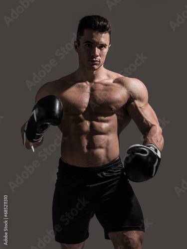 A muscular young man in studio with no shirt and boxing gloves © theartofphoto