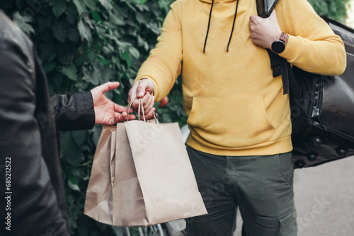 Man food delivery in yellow uniform and thermal bag ,handing food bags groceries to customer .concept food delivery groceries