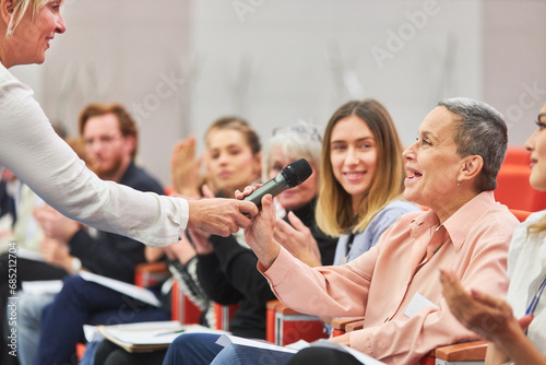 Speaker giving microphone to audience at business event