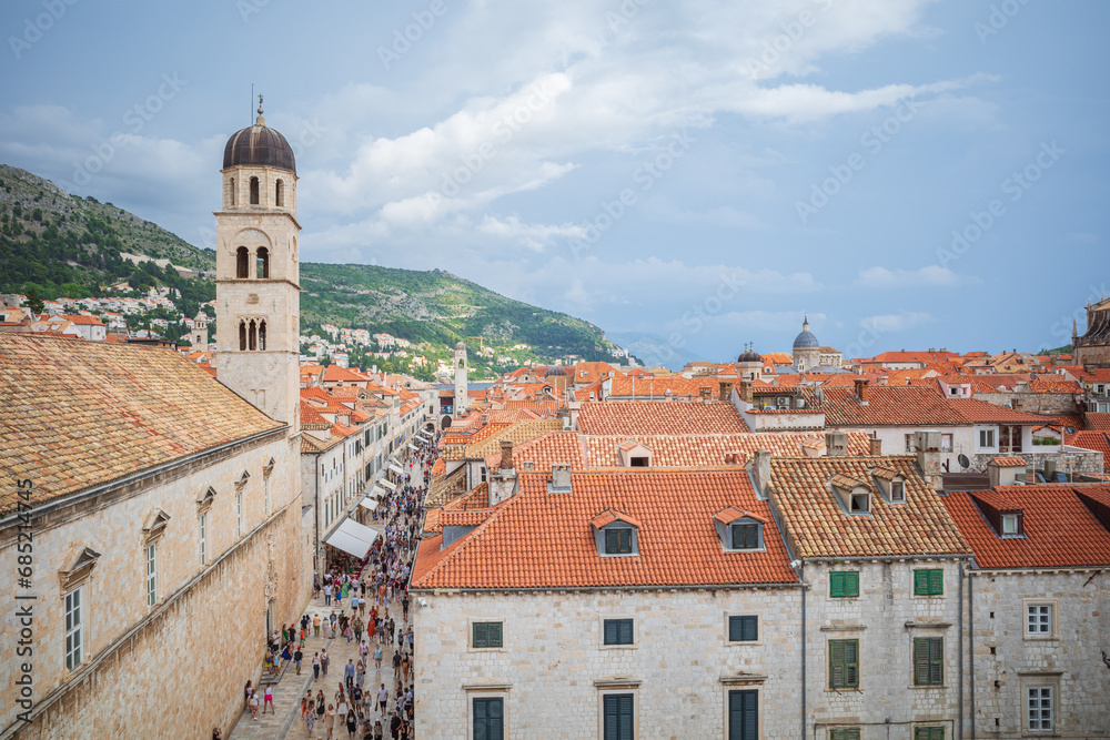 View to the red roofs of Dubrovnik Old town on summer day. Crowd of people walking in the streets