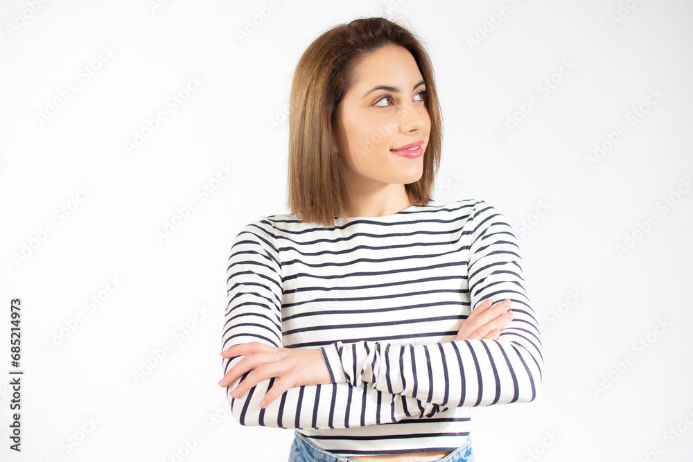 Portrait of a smiling young woman standing with arms folded and looking away at copy space isolated over white background Portrait of a smiling young woman standing with arms folded and looking away at copy space isolated over white background