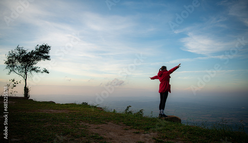 Portrait of a beautiful young woman in red coat on the background of blue sky © Wosunan
