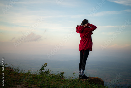 Portrait of a beautiful young woman in red coat on the background of blue sky