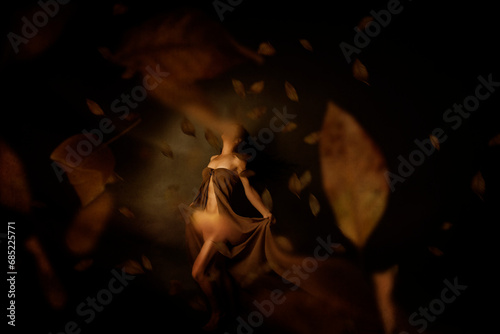Mystical woman dancing amongst floating autumn leaves photo