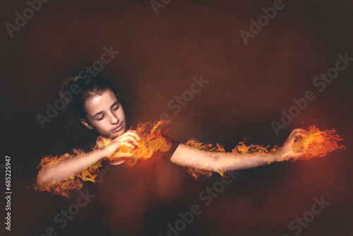 Portrait of a teenage girl doing a magic trick setting her arms on fire photo