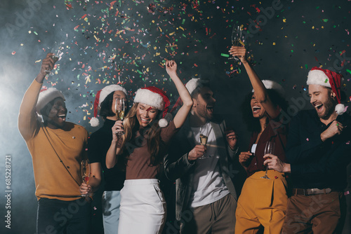 Group of young people dancing and throwing confetti while enjoying New Year party in night club