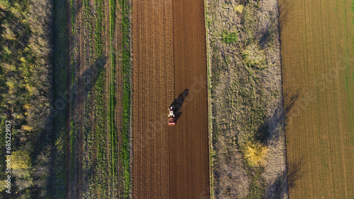 Aerial view of a tractor sowing wheat in a ploughed field, San Giuliano Nuovo, Alessandria, Piedmont, Italy photo