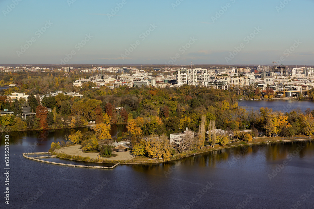 Bucharest from above, aerial view over Herastrau (King Michael I) Park, lake and the north part of the city with office building photographed during a autumn day after sunrise.