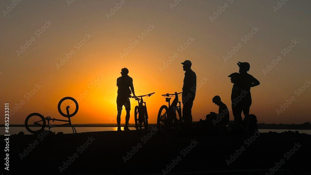 Silhouettes of the people on the beach with mountain bikes