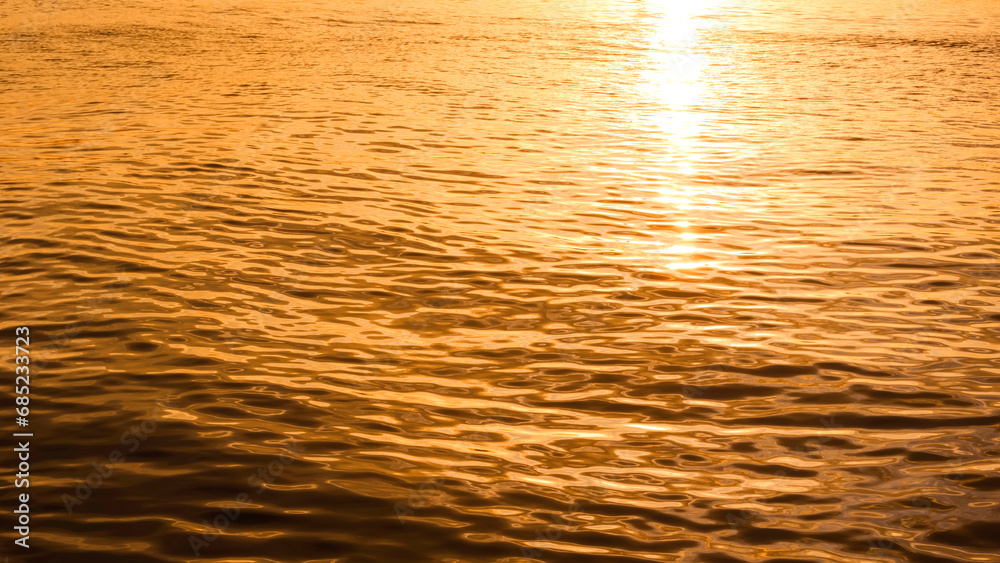 Beautiful golden sunlight reflection with ripple on sea surface in morning sunrise time