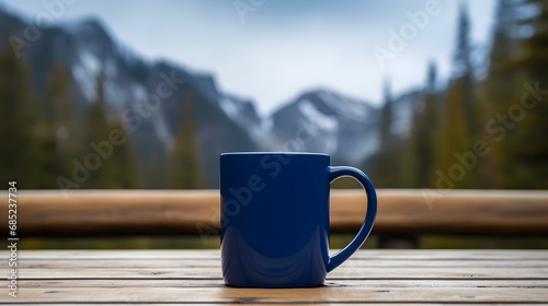 Close up of a navy blue Mug on a wooden Table in the Mountains. Blurred natural Background