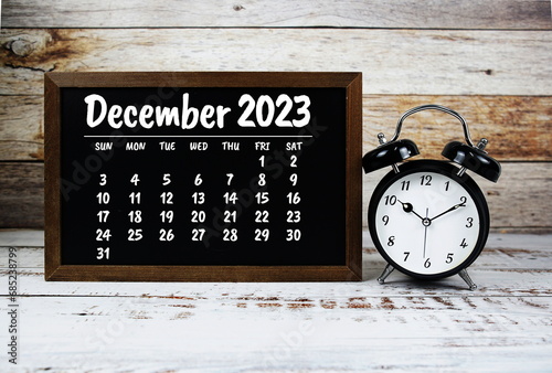 December 2023 monthly calendar and alarm clock on chalkboard background