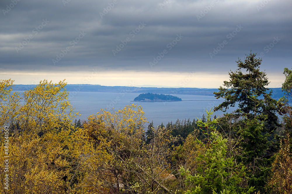 2023-11-28 A VIEW OF THE PUGET SOUND AND A SMALL ISLAND WITH WHIDBEY ISLAND INTHE BACKGROUND WITH A CLOUDY SKY FROM CAMANO ISLAND
