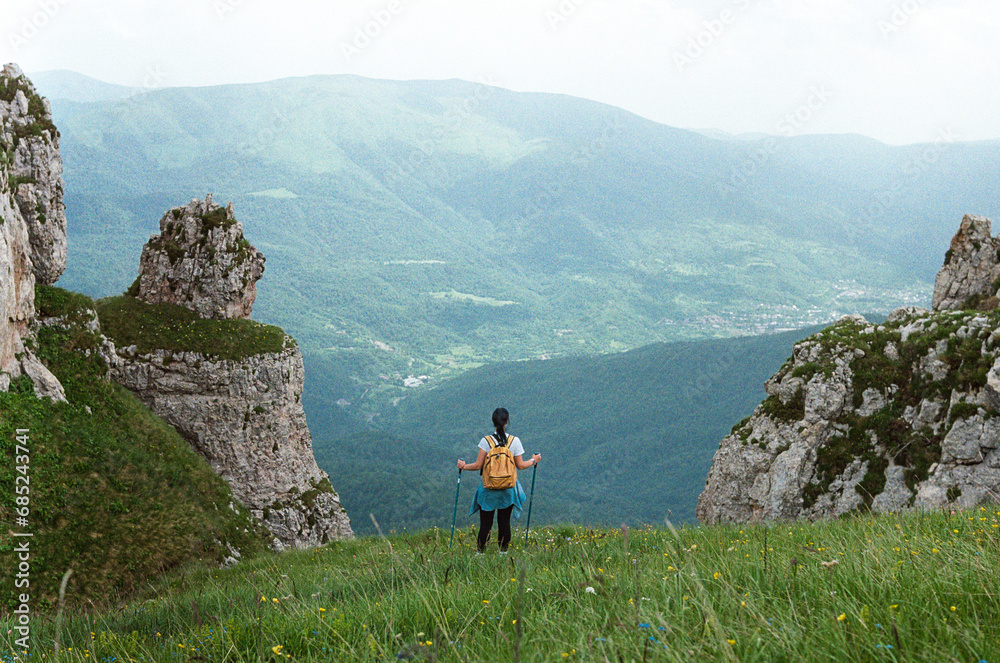 A tourist girl stands in the mountains and looks ahead - film photo