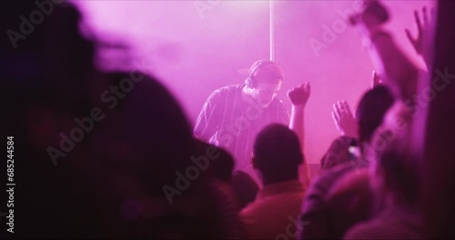 Crowd, dance and nightclub DJ with rave, techno or disco lights for music, party and celebration or festival event. Group of people or audience hands at club for cheers, listening and energy in dark photo