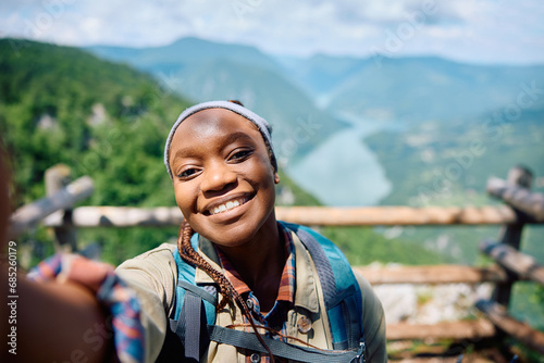 Happy black woman taking selfie while hiking in mountains.