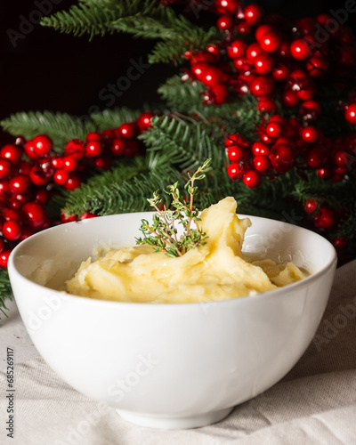 Close-up of white bowl with mashed potatoes, on white tablecloth with Christmas decoration, vertical, with copy space