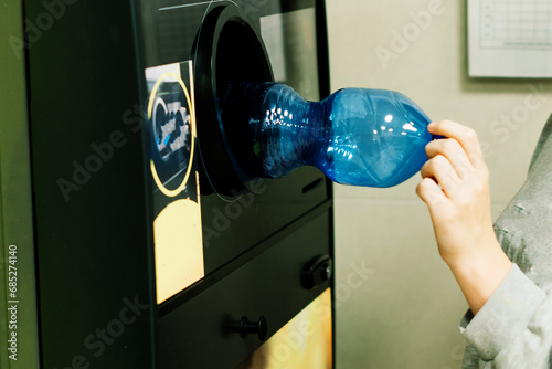 Reverse vending recycling machine that dispenses cash. Man hand puts plastic bottle to the machine