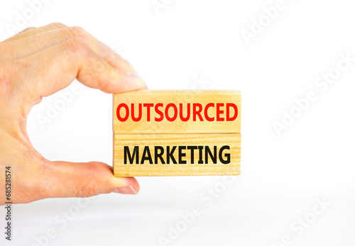 Outsourced marketing symbol. Concept words Outsourced marketing on beautiful wooden blocks. Beautiful white table white background. Businessman hand. Business Outsourced marketing concept. Copy space.