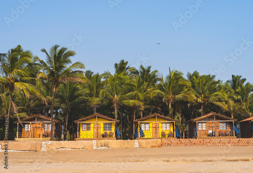 Colorful huts in Agonda beach with palm trees background in Goa, India