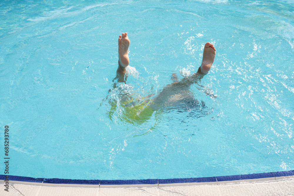 Youthful legs kick, submerged in water; a moment of pure leisure, reflecting universal aquatic fun.