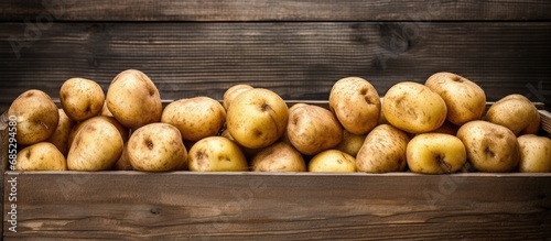 Organic potatoes in wooden crate on aged table copy space image