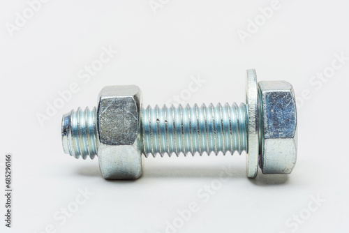 group of bolts and nuts on a white background. bolts, washers and nuts assembled on a light background. photo of fasteners with threads for the catalog
