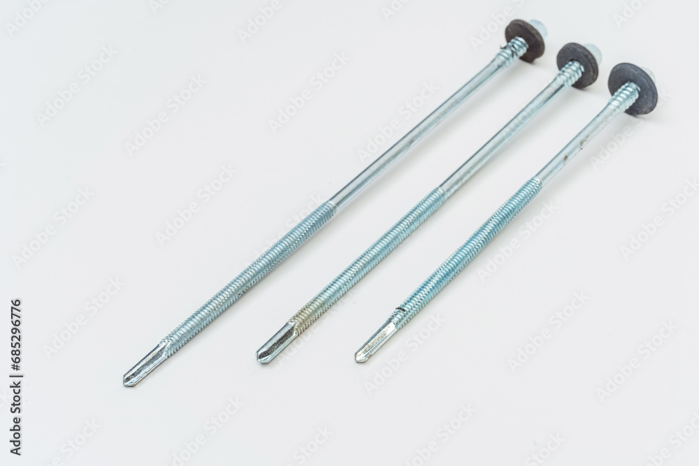 long screws on a white background. self-tapping screws with a tip for metal and concrete on a light background. photo of bolts in a photo studio for a catalog long screws on a white background. self-tapping screws with a tip for metal and concrete on a light background. photo of bolts in a photo studio for a catalog