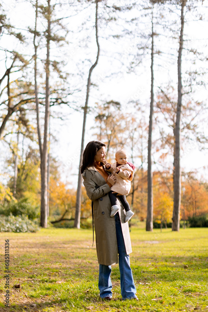 Fototapeta premium Young woman holding cute baby girl in the autumn park