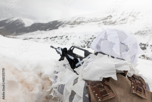 Un soldado de alta montaña con su fusil camuflado en un paisaje de montaña nevado.