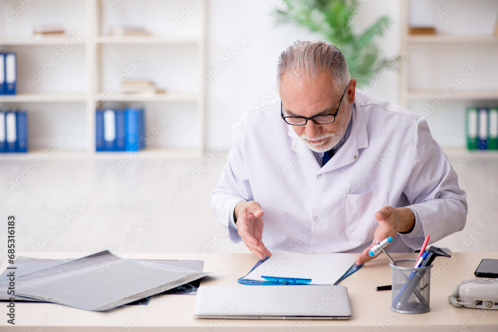 Old male doctor working in the clinic