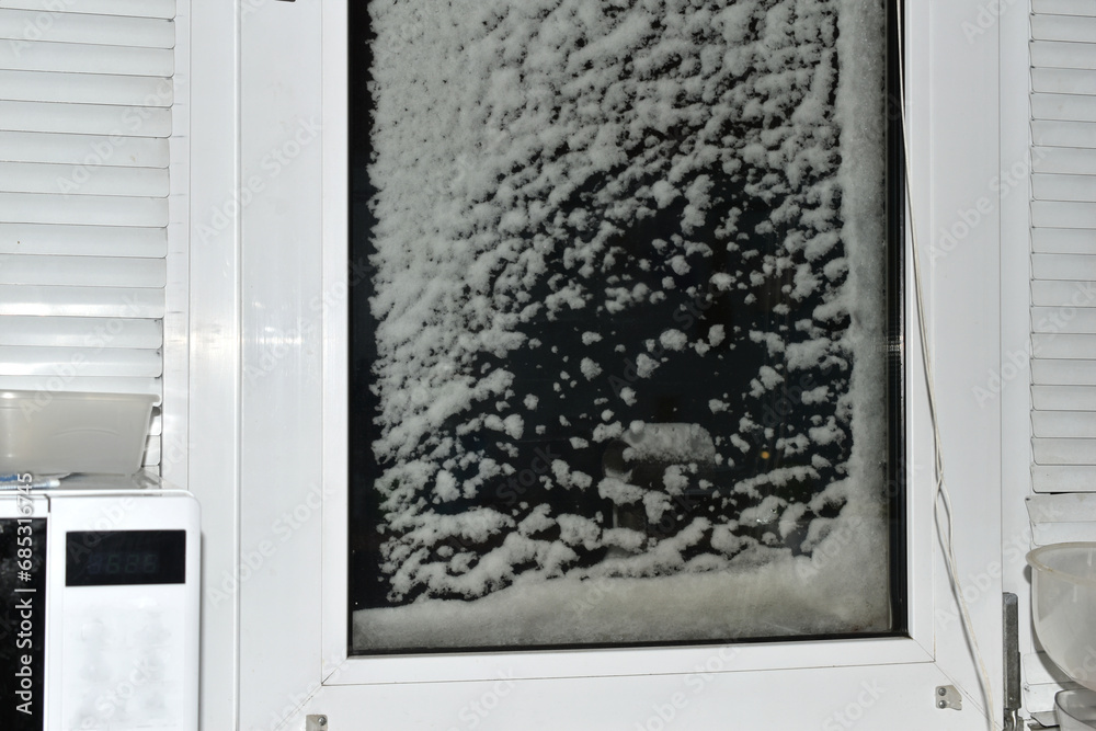 Fototapeta premium Thick, wet snow covered the window glass. The photo was taken from inside the room.