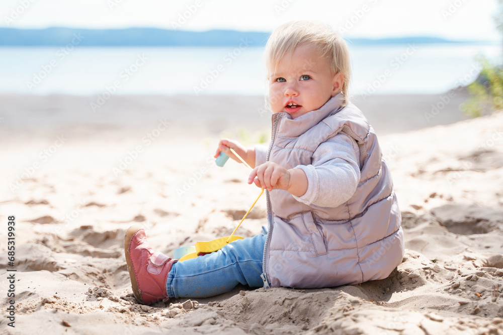 An adorable little toddler is walking along an empty cold beach with a duck toy, a beautiful landscape and a cute childhood concept An adorable little toddler is walking along an empty cold beach with a duck toy, a beautiful landscape and a cute childhood concept