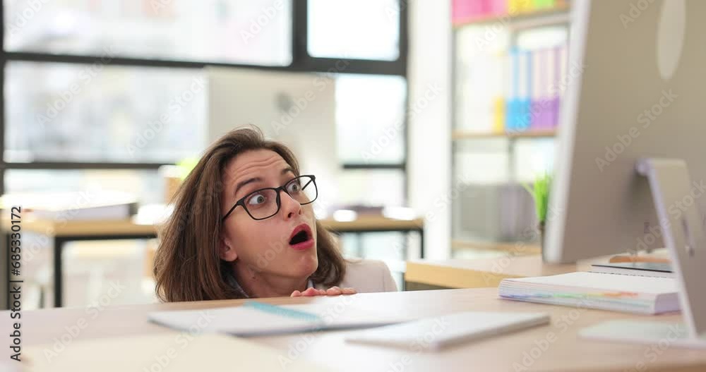 Frightened and shocked woman in panic at table looking at computer screen Frightened and shocked woman in panic at table looking at computer screen