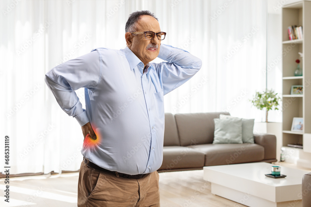Mature man with painful back and neck standing at home