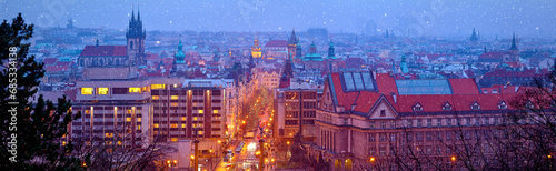 Prague Czech Republic. Wide panorama. Panoramic view at nighttime winter old town with falling snow, towers of prague. Illuminated street aerial Christmas time during seasonal holidays.