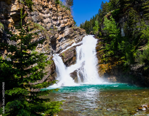  A scenic view of Cameron Falls in Waterton, Alberta on a sunny day.