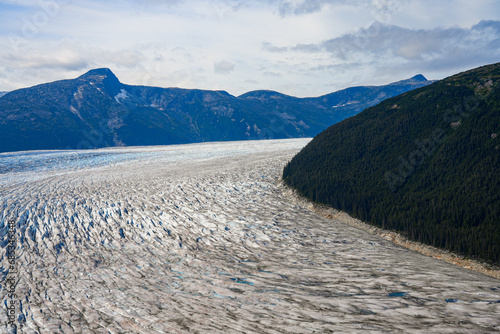 Aerial view of the glaciers located along the Taku Inlet, which are part of the Juneau Icefield in Alaska, USA - Curvy flow of ice covered with shear crevasses, cracks and fissures photo