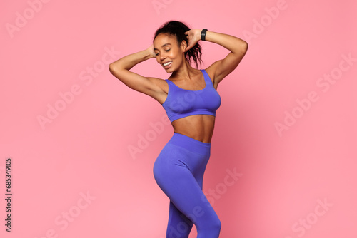 Fototapeta Naklejka Na Ścianę i Meble -  Fit Black Woman Wearing Sportswear Standing Over Pink Studio Backdrop
