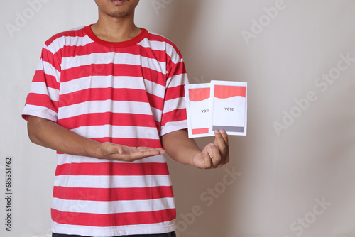 Voting papers for general elections or Pemilu for the president and government of Indonesia. Cropped portrait of asian man holding ballot. photo